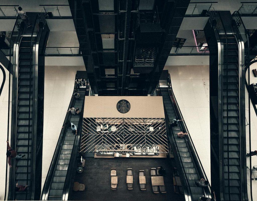 View of a stylish coffee shop and escalators from above in a mall.